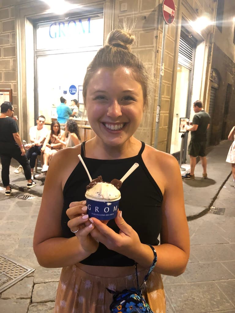 Kendra smiling with a cup of gelato on a city street at night