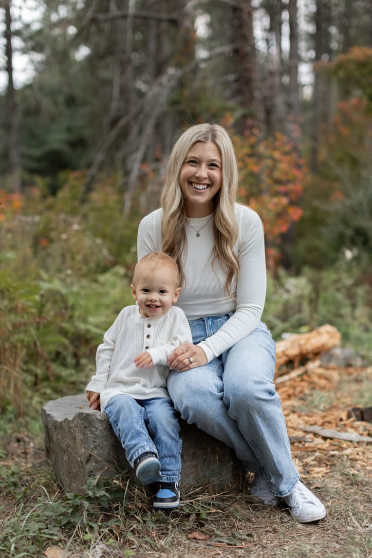Kendra laughing with her toddler on a rock in the forest